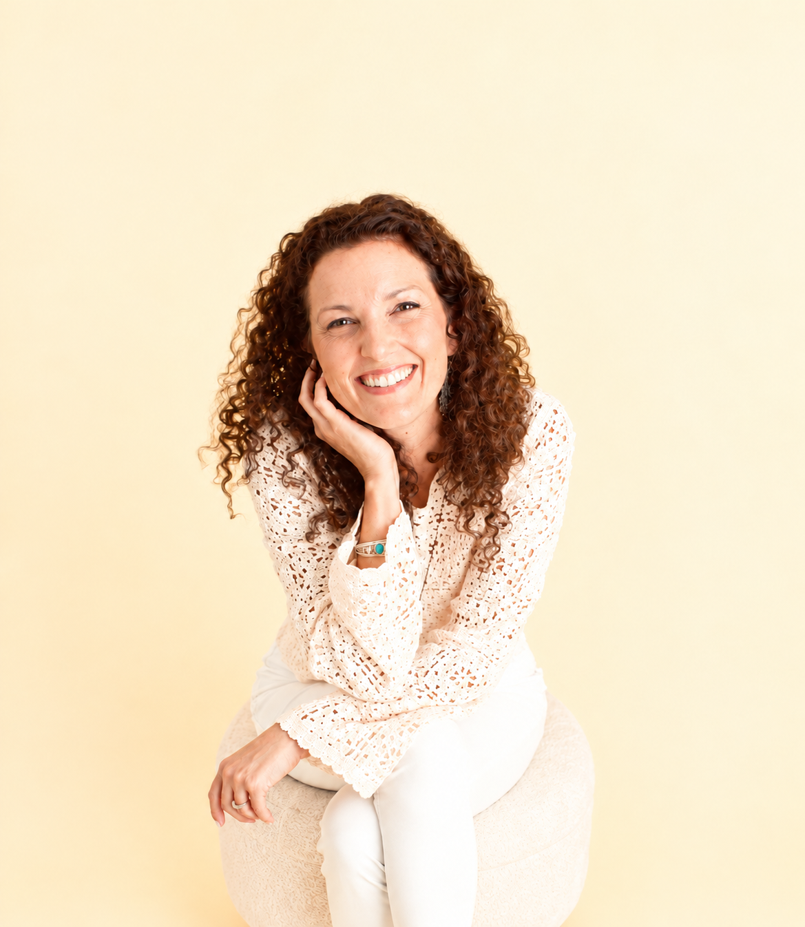 Arianna Day smiling, seated in a cream outfit